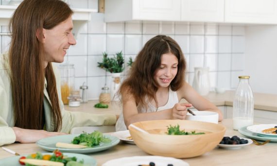 Father and daughter sharing a joyful breakfast at home in the kitchen.