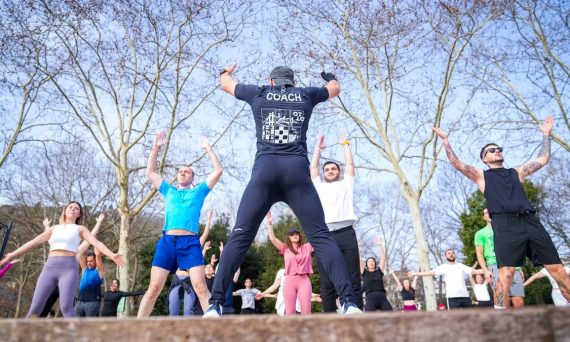 Group exercise session in a sunny Istanbul park led by a fitness coach outdoors.